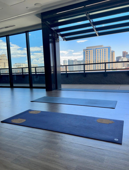 Yoga mats with different thicknesses and Cork Helping Hands grip accessories in a yoga studio setting.