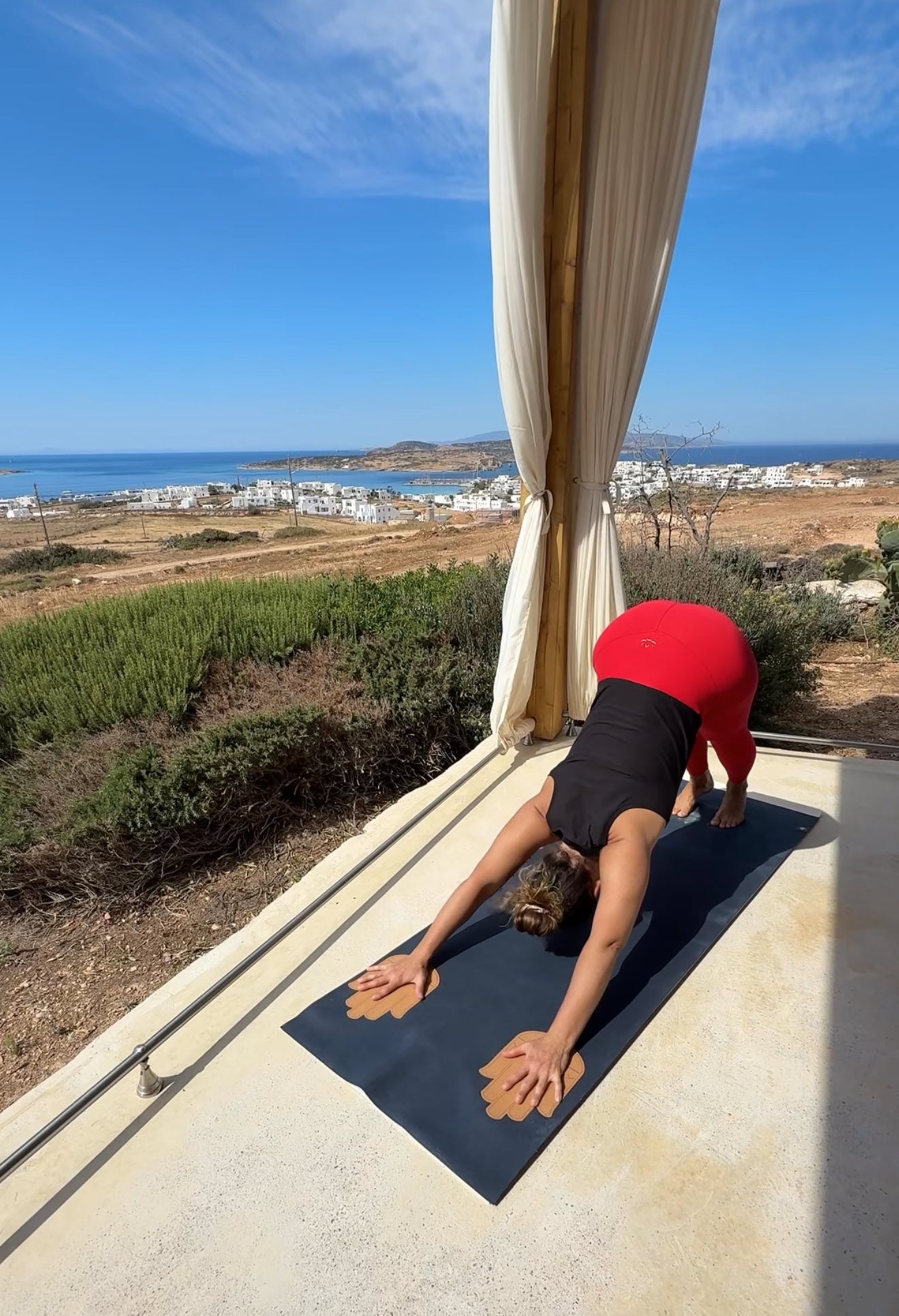 Yogi on a mat with Cork Helping Hands with a scenic view of the ocean and buildings in the background.